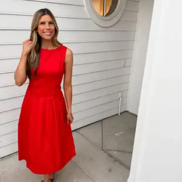 Corrine-wearing-red-pleated-dress-2-scaled