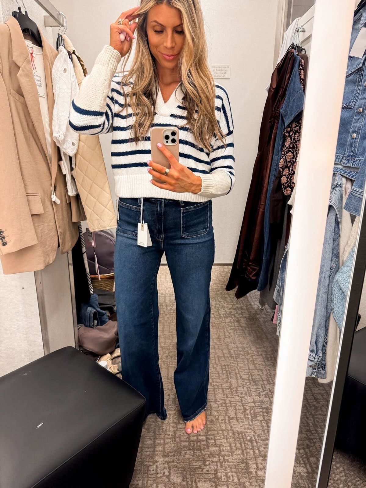 A woman in jeans and a striped shirt taking a selfie.