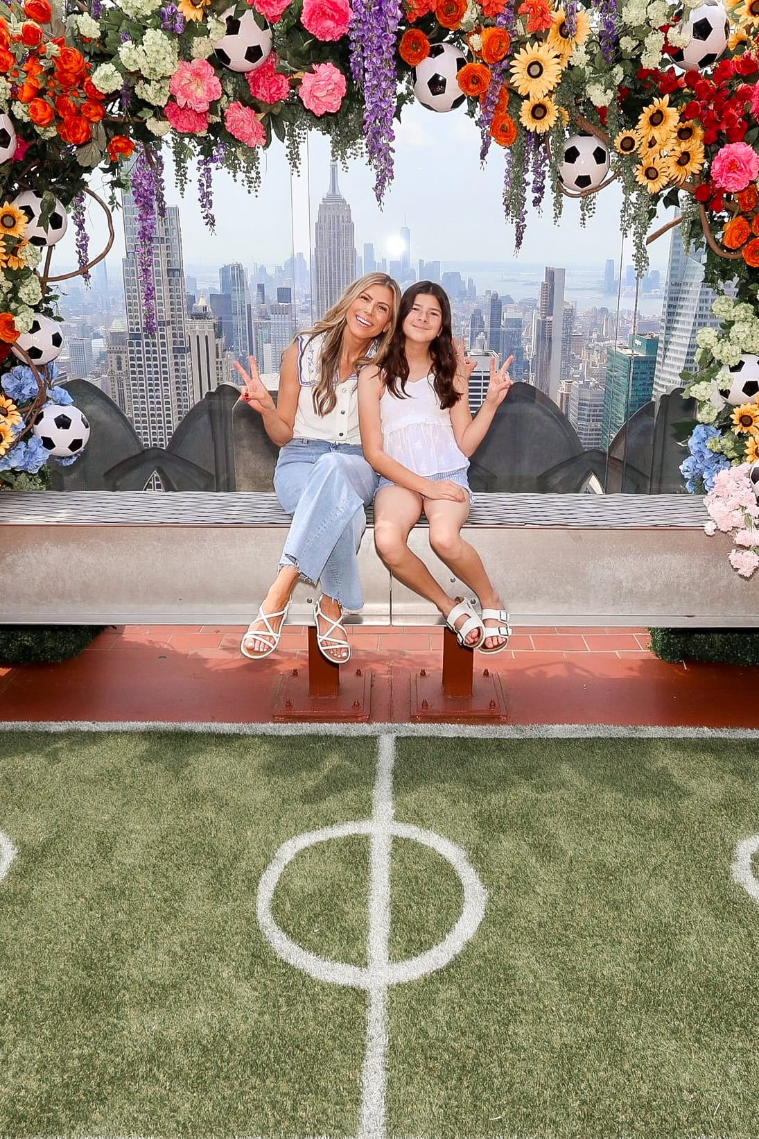 Mom and tween daughter throwing peace signs sitting at the flower bench at Top of the Rock in NYC