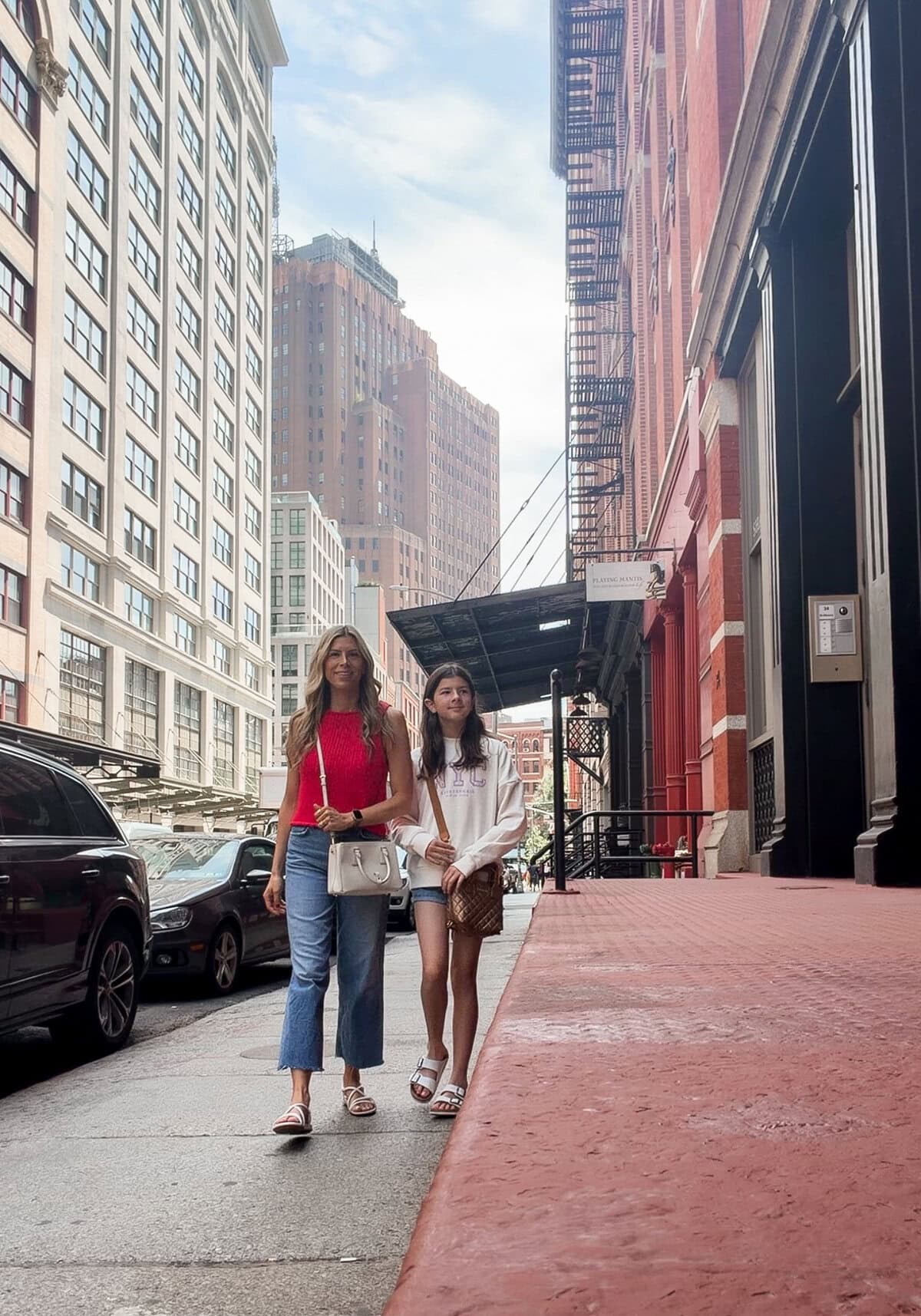 Mom in red Free People tank with AGOLDE wide-leg jeans and tween in abercrombie NYC sweatshirt walking down a SoHo street in New York City