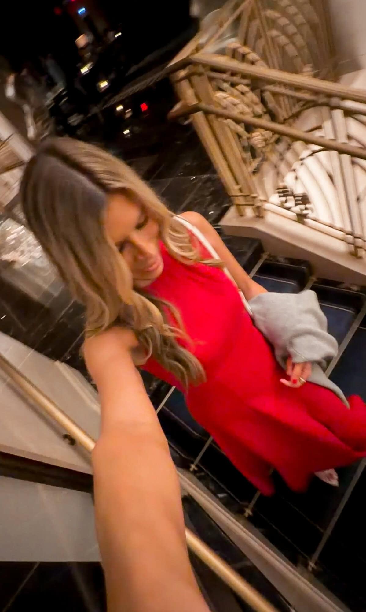 Corrine in red dress carrying lilac cardigan at theater