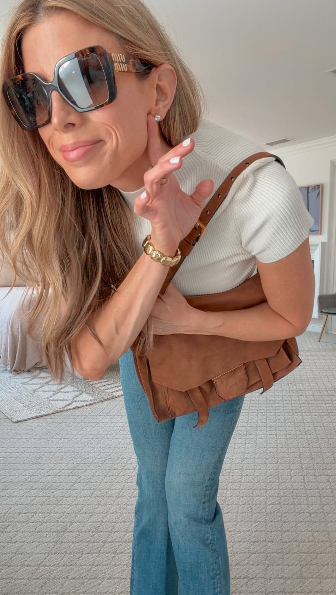Corrine in a mock-neck top, bootcut jeans, and a suede shoulder bag