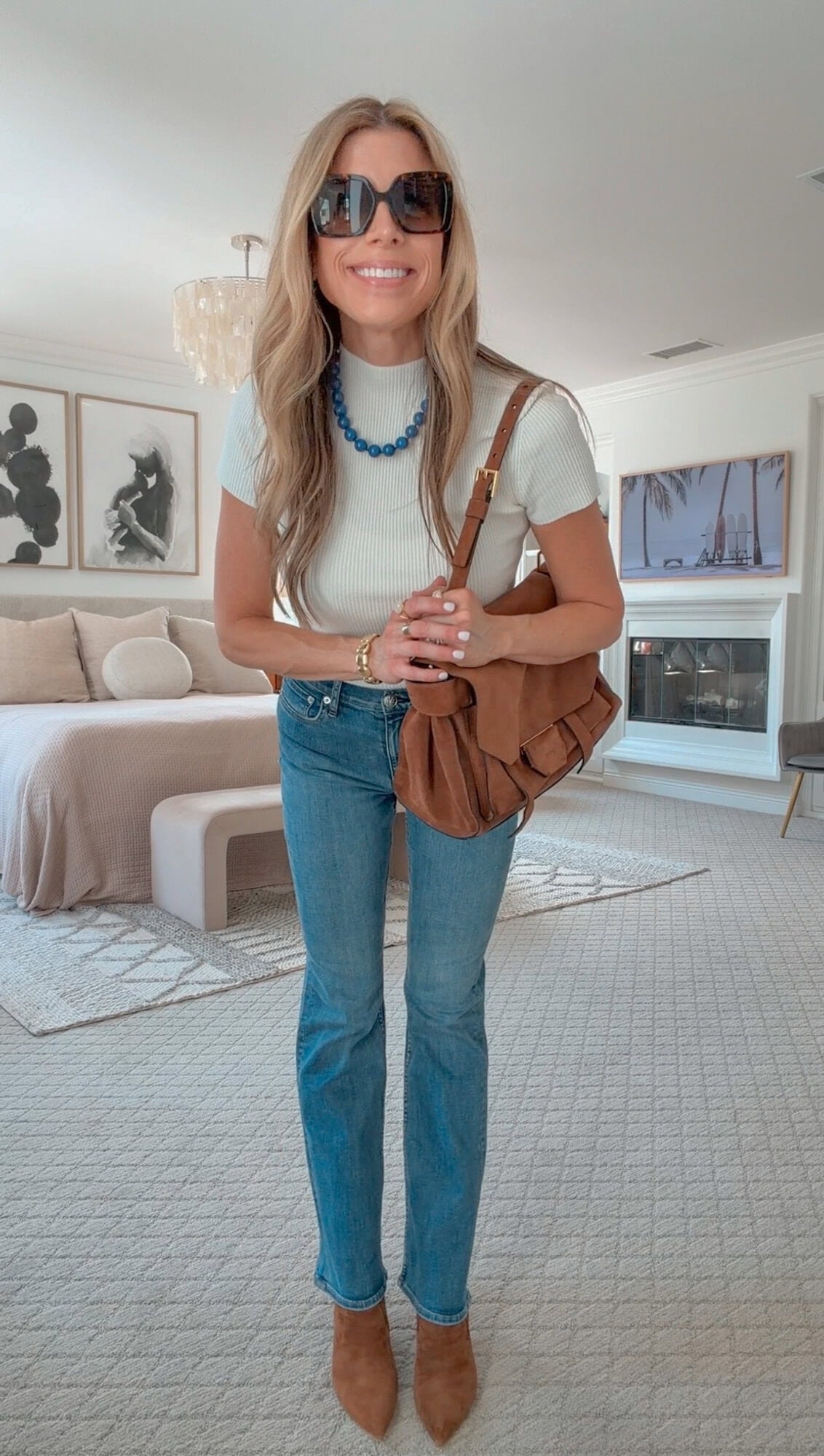 Corrine in a suede jacket over a mock-neck top with bootcut jeans and booties