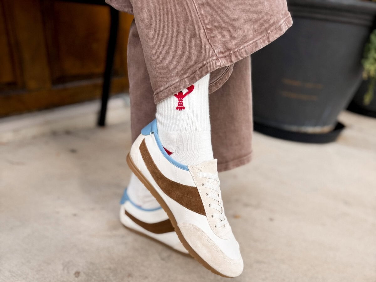 Close up of the Vince low profile runner sneaker in cream with a brown suede stripe and gum sole