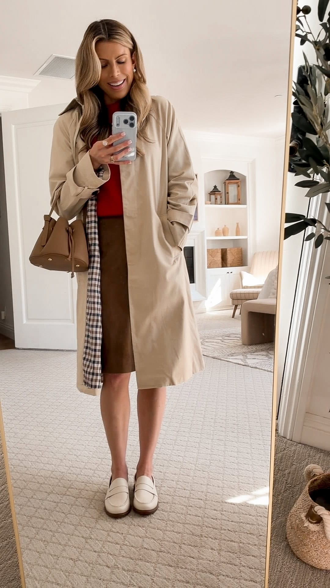 Corrine wearing a red cashmere sweater and brown suede cargo skirt from Anthropologie with a trench coat