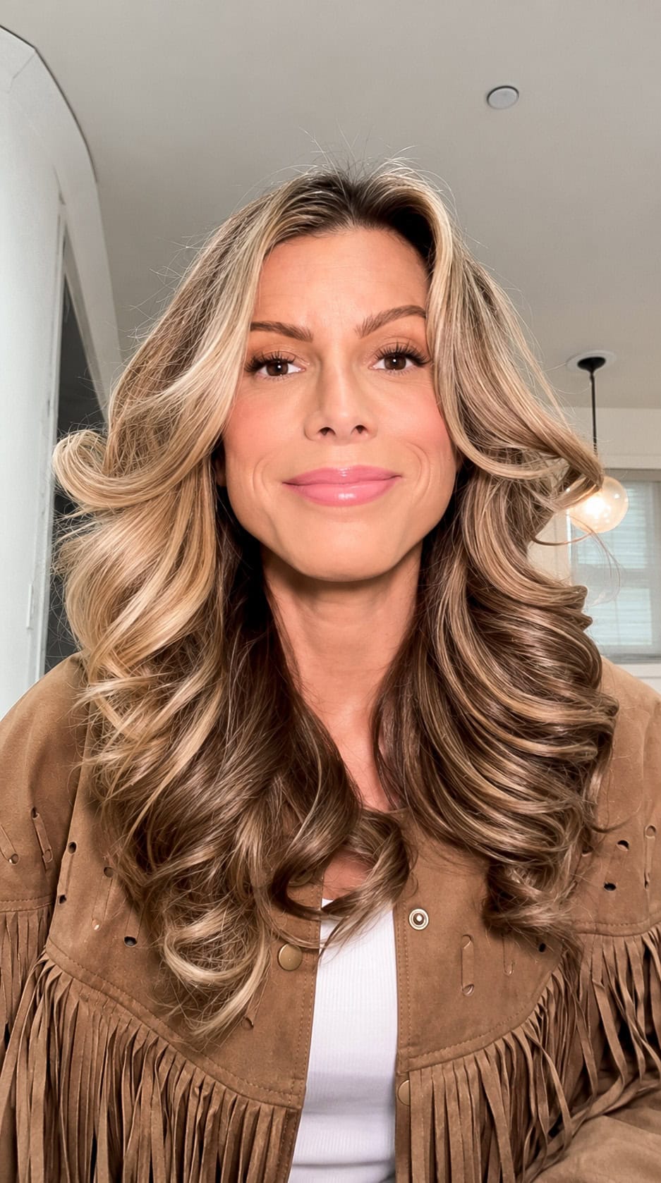 Corrine Stokoe wearing a brown fringe faux suede jacket over a white top